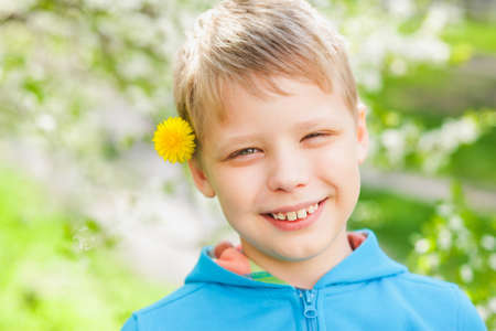 Closeup portrait of cute funny little boy isolated over green blooming trees background. Caucasian...