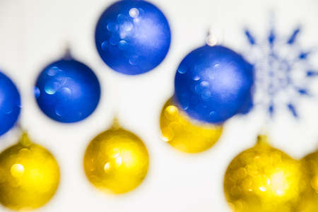 Christmas defocused festive background. New Year blurry blue and gold colors brilliant beautiful balls and snowflakes hanging on silver ropes isolated on white.  Horizontal color photography.の写真素材