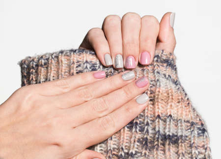 Closeup view of white hands of woman with beautiful modern grey and pink manicure design. Horizontal...