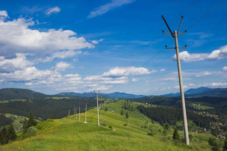 Old rusty power lines at scenic green hills of mountain at bright blue sky background in countryside...