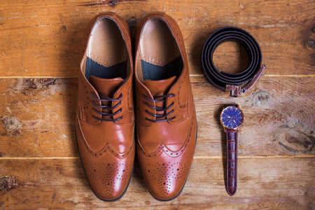 Closeup of elegant stylish brown male formal accessories isolated on brown wooden background.