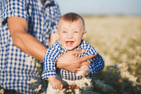 Closeup portrait of funny happy laughing toothless caucasian baby in hands of strong daddy.の写真素材