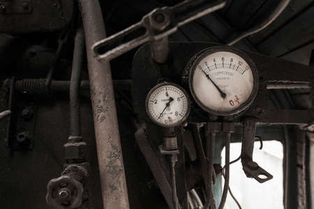 Details of interior of abandoned old rusty soviet locomotive at platform. Two braking vintage manometers and rusty pipes. Written in russian on white surface of devices: Braking manometer.の写真素材