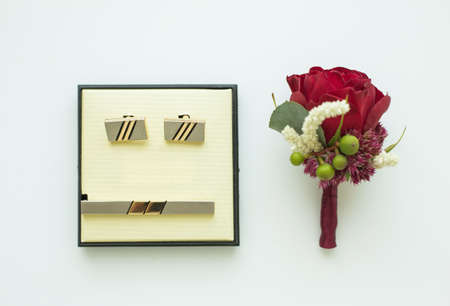Top view of male cufflinks and small red boutonniere isolated on white background. Horizontal color...