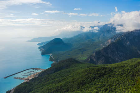 Beautiful sunny aerial view of Turkish marine landscape. Picturesque green mountains and fluffy white clouds over peaks. Charming nature background. Antalya city. Horizontal color photography.の写真素材
