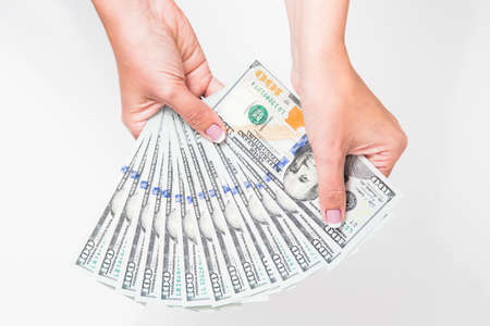 Closeup up view of white female hands holding many 100 dollars paper bills isolated on white...