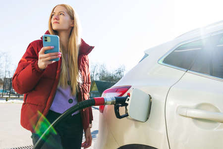 A beautiful young woman pays for a gas station using an app on her phoneの写真素材