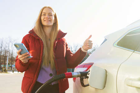 A beautiful young woman pays for a gas station using an app on her phoneの写真素材