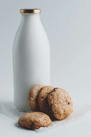 Homemade cookies with pieces of chocolate on the background of a bottle of milk on a white backgroundの写真素材