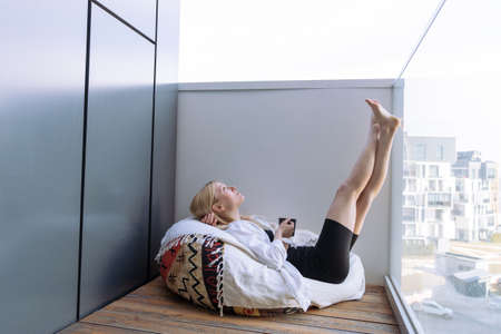 A young woman is resting on the balcony and drinking coffee