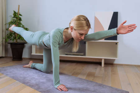 A young woman in the lotus position hands in the namase pose. The process of relaxation during a workout at homeの写真素材