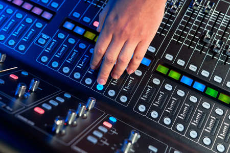 A man's hand controlling a professional sound remote control