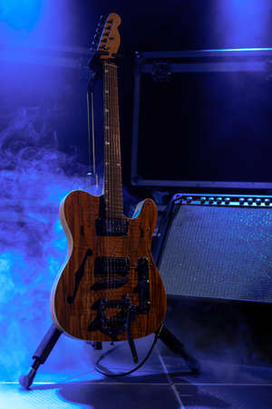 Wooden electric guitar with amplifier on stage with smokeの写真素材