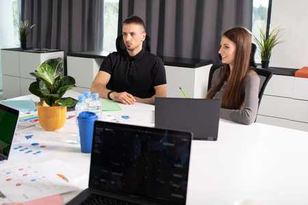A man and a young woman colleagues at the table discuss the company's plansの写真素材