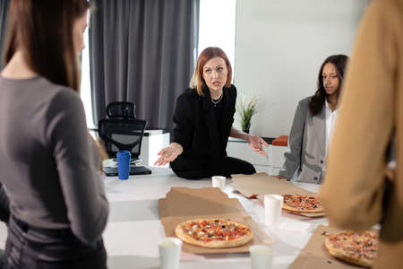 Colleagues eat pizza in the office during their lunch breakの写真素材