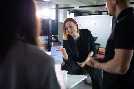 A young woman communicates with colleagues during lunch in the officeの写真素材