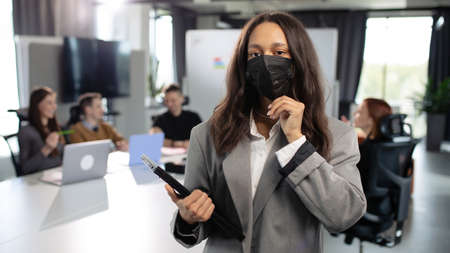 African american woman wearing a protective mask in the officeの写真素材