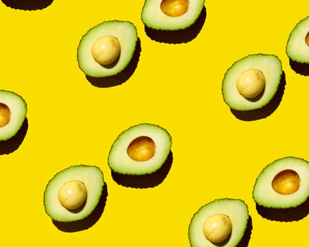 Top view of the pattern of a cut green avocado with a stone on a yellow background. natural vegetablesの写真素材