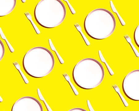 Plastic empty plate, fork and knife on a yellow background. pattern top viewの写真素材