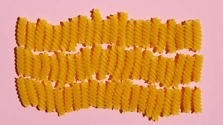 Raw pasta spirals on a pink background. top view