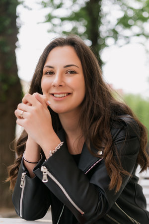 Portrait of a woman. A model in a leather jacket poses on the outsideの写真素材