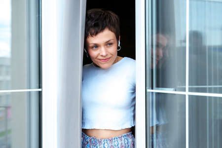 A young woman wearing headphones on the balcony in the morning. A calm summer morningの写真素材