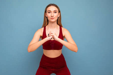 A young woman in a tracksuit does exercises on a blue backgroundの写真素材