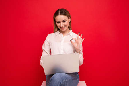 Young woman in a white shirt making a video call from a laptopの写真素材