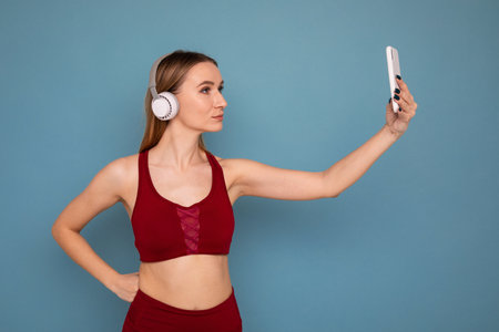 A young woman in a tracksuit and headphones takes a selfieの写真素材