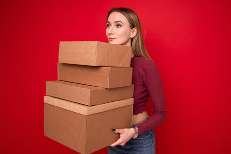 A young woman holds cardboard boxes on a red backgroundの写真素材