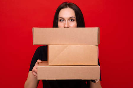 Young woman with paper boxes on red backgroundの写真素材