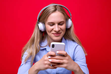 A young woman in a shirt listens to music from her phone