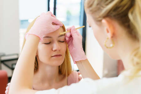 Eyebrow master while removing facial hair with wax. skin and hair care