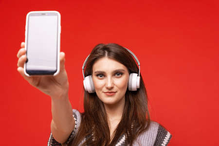 A young woman listens to music with headphones on her mobile phoneの写真素材