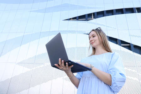 Young woman typing on a laptop on the street