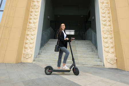 A young woman rides an electric scooter in the city. Eco friendly transportの写真素材