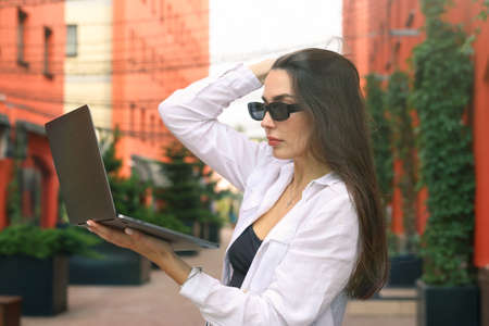 A freelance young woman works on a laptop on the streetの写真素材