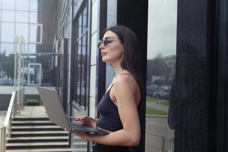 Portrait of a beautiful young woman with a laptop on the streetの写真素材