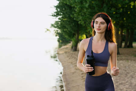 Training outside, an active lifestyle. Athletic woman while jogging on the beach