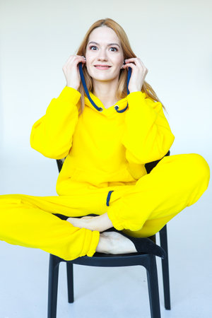 A young woman indulges in front of the camera in a bright yellow tracksuitの写真素材