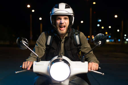 Portrait of a screaming pizza delivery guy. A man on a scooter delivers products in the evening in...