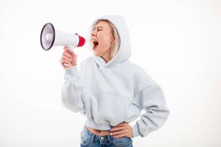 A young woman shouts into a megaphone on a white backgroundの写真素材