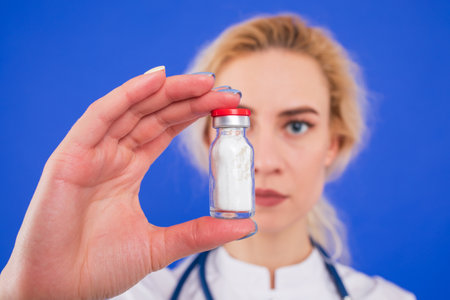 Nurse with a bottle of white medical suspension on a blue backgroundの写真素材