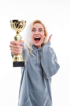 Emotions of a female athlete after winning a competition. The model holds the gold cup of the...
