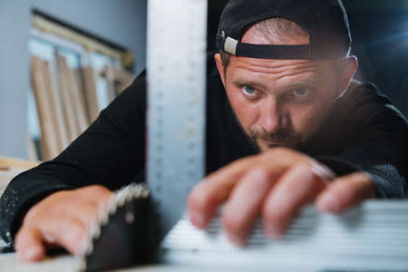 A master carpenter sets up a circular sawing machine before work. Small business, own productionの写真素材