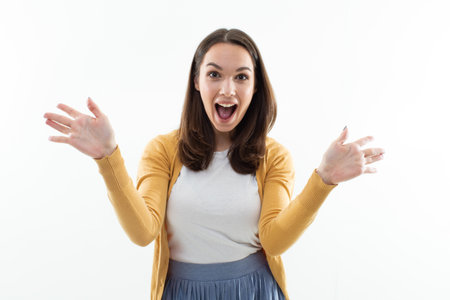A joyful young woman looks into the camera. Studio portrait of an emotional brunette on a white background isolatedの写真素材