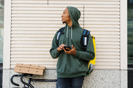 Portrait of an African-American courier outside. A delivery man on a bicycle. Fast delivery from...