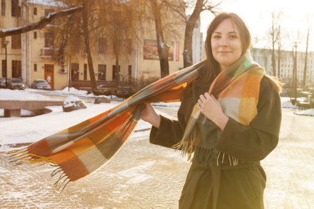 Portrait of a beautiful young woman in a coat posing on the street.