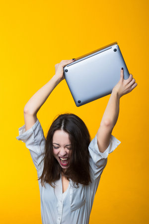 Fatigue at work. Young woman wants to smash laptop.の写真素材