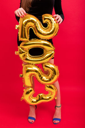 Close-up of the figures of the new year 2023 against the background of beautiful female legs in heelsの写真素材